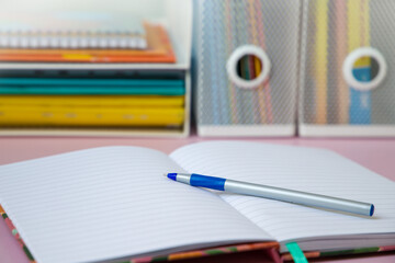Notebook with pen on pink background. Back to school concept.