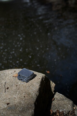 Organic handmade blacksoap bars placed by a flowing stream, symbolizing freshness and hydration....