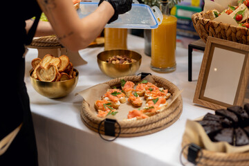 Elegant catering setup featuring smoked salmon appetizers, fresh juices, and assorted snacks on a white tablecloth, showcasing culinary artistry