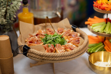 Close-up of a catering platter featuring appetizing canapés topped with cured ham and fresh arugula, ready to be enjoyed at a corporate event