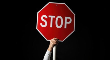 Hand Holding Stop Sign: A close-up shot of a hand holding a stop sign, showcasing its vibrant red color, conveying a strong message of authority, safety, and direction.