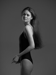 black and white portrait of a young woman in a black bodysuit with long hair, posing confidently...