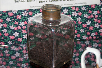 Coffee beans in a glass bottle on a background of flowers