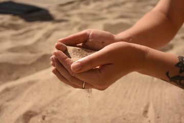 Sand in human hands, beach background, summer vacation concept, close-up.