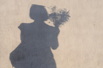 Shadow of a woman holding a bouquet of flowers on the wall. Shadows on the walls.