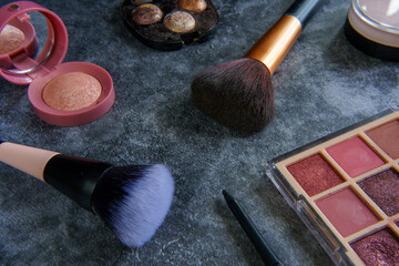 Makeup products and tools arranged on a dark background. 