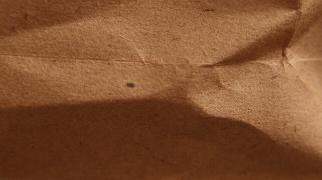 Wrinkled kraft folds on fibrous brown paper surface, abstract crumpled texture with organic depth and natural imperfections