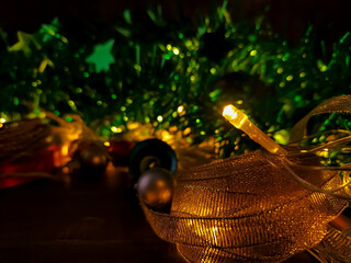 Festive decorations featuring an arrangement of greenery, illuminated by warm yellow lights, are shown against a dark wooden surface. 