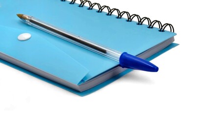 Closeup view of a blue spiral notebook with a blue pen, isolated on white background.