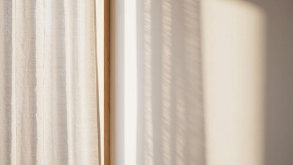 Fototapeta premium Soft natural sunlight casting delicate shadows on a light-colored wall and textured curtain, creating a minimalistic and serene atmosphere indoors