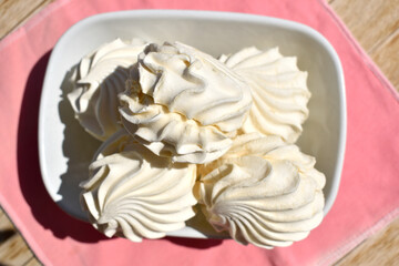 white marshmallows in white dishes on a pink napkin top view