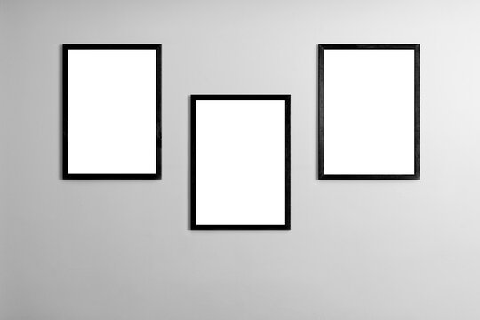 Modern minimal interior with one two three four five blank black wooden photo frames light gray wall, mockup template for artwork, posters or prints, Scandinavian design, home decor, gallery wall