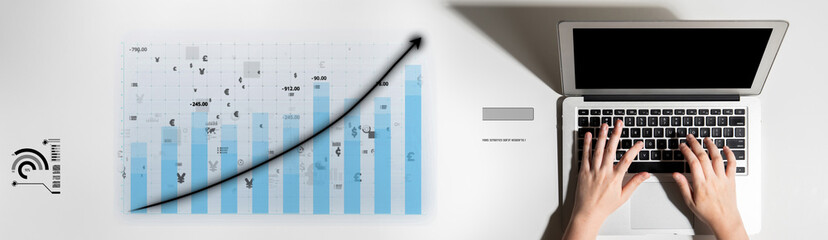 A laptop with hands typing rests beside a chart displaying an upward trend, symbolizing growth and...
