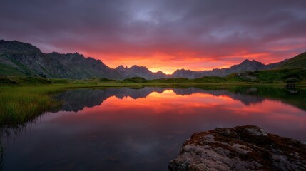 Fototapeta premium Dramatic sunset clouds rolling over a rugged mountain range with vibrant colors reflecting on still waters