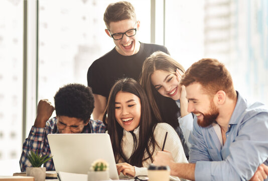 We did it. Euphoric students watching exam results on laptop, sitting together in college library