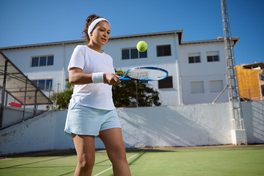 Woman Practicing Tennis Skills by Bouncing Ball on Racket Outdoors - Powered by Adobe