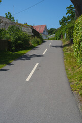 Uphill road leading to house with red roof.