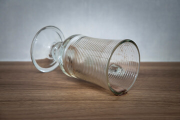 Xícara suja de café, chocolate quente, de vidro, caída sobre uma mesa de madeira com um pouco de café, chocolate quente escorrendo sobre a mesa. .Fundo desfocado.