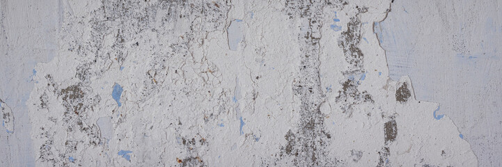 Vintage wall texture. The weathered, rough surface of a plastered concrete wall with faded, peeling paint. Wide panoramic texture for background and design.