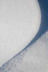 Beautiful winter background with snowy ground. Natural snow texture. Wind sculpted patterns on snow surface. Closeup top view with copy space.