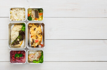 Healthy restaurant food background. Eating right concept. Fresh diet daily meals delivery. Fitness nutrition, vegetables, meat and fruits in foil boxes. Top view, flat lay on wood with copy space