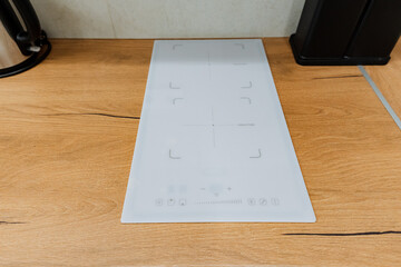 A modern induction cooktop is elegantly placed on a beautiful wood countertop, showcasing its sleek design in a contemporary kitchen setting that highlights both style and functionality