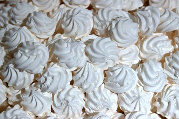 A close-up, top-down view of a pile of small, swirled white meringues.