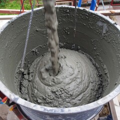 Gray concrete mix being poured into a large container
