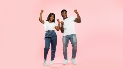 Wow, Yes. Overjoyed young black man and woman cheering and shaking clenched fists, looking at...