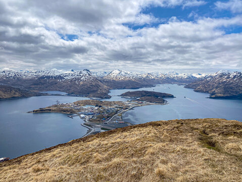Panoramic aerial view of Unalaska Island with airport port and mountains. Alaska Remote Aleutian Island town of Unalaska with harbor and snowy peaks