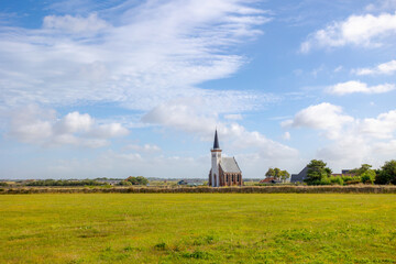 Typical landscape of Texel island with small village and picturesque church (Hervormde kerk) under blue sky and white clouds, A little town on the wadden islands, Den Hoorn, Noord Holland, Netherlands