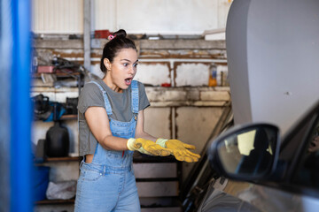 A shocked mechanic in overalls reacts while working in a garage, highlighting a moment of surprise and problem-solving.
