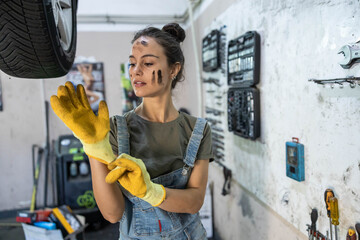 A mechanic readies herself with gloves in a garage, showcasing her focus and determination before...
