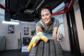 The image showcases a smiling mechanic joyfully holding a tire, embodying a sense of accomplishment...