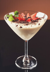 Tiramisu in glass. Italian cream dessert with cocoa, fresh strawberries and mint on dark glassy background with reflection and copy space