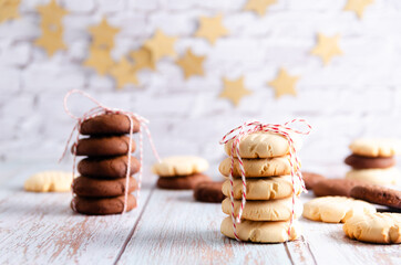 Stacked vanilla and chocolate cookies tied with a red and white string, some cookies on a light...
