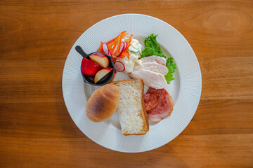 Healthy breakfast plate with bread, ham, chicken and fresh salad
