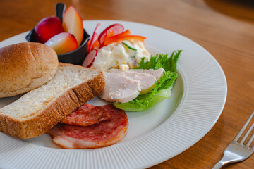 Healthy breakfast plate with bread, ham, chicken and fresh salad
