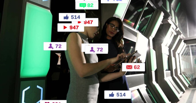 Collaborating women colleagues analyzing data on tablet in tech corridor, with social media metrics - Powered by Adobe