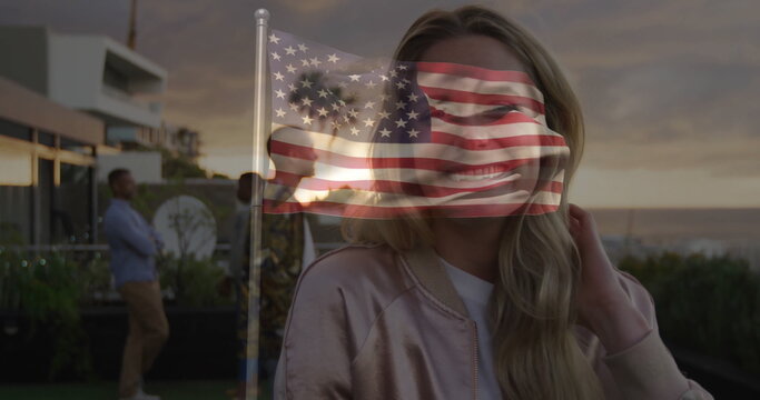 Standing woman in satin jacket overlooking ocean from rooftop, with railing and US flag overlay