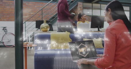 Working Asian woman using laptop on navy-blue couch by gold lamp at office lounge, copy space