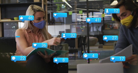 Two masked colleagues discussing binder in open-plan office, with floating icons and sticky notes