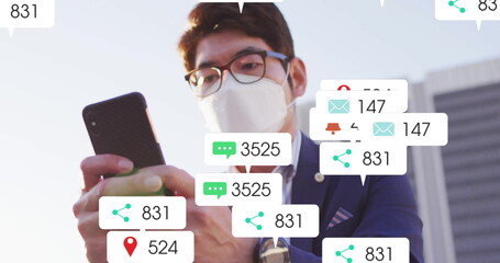 Masked Asian businessman holding smartphone, viewing alerts in business plaza, with chat overlays