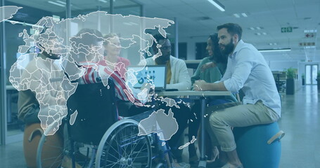 Collaborating team sitting around round table in modern office, using open laptop and wheelchair