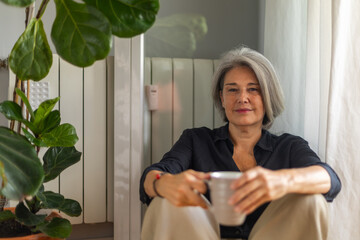 Serene mature woman enjoying a cup of coffee by the window