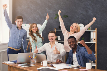 Young business team enjoying success, looking at computer screen, celebrating successful project,...