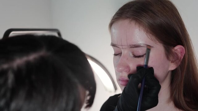 Specialist finalizing brow shape before permanent makeup