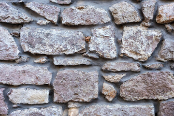 Old textured stone wall with rough surface and natural cement joints, historical architecture background for restoration or construction themes