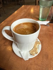 Cup of Americano coffee with crema served with animal-shaped shortbread cookies in a cafe.