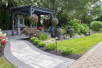 Wooden gray pergola on pavers with stone fireplace and waterfall urns landscape design idea for...